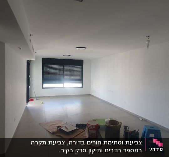 חדר עם ציוד לצביעה, כולל דלי צבע ומברשת.